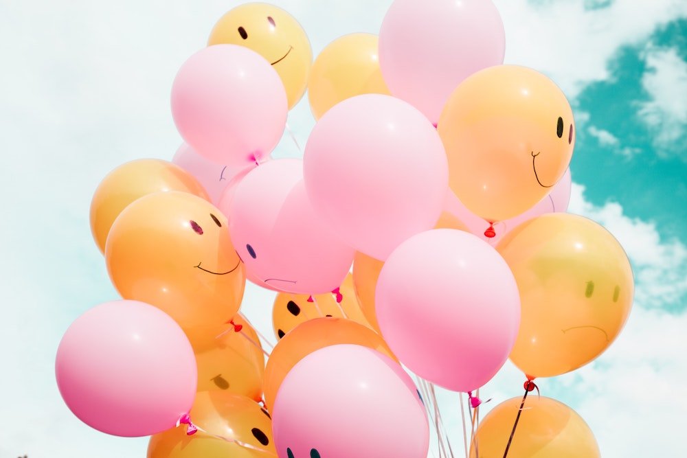 pink and yellow balloons with smiley faces