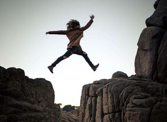 Woman jumping from one rock to another