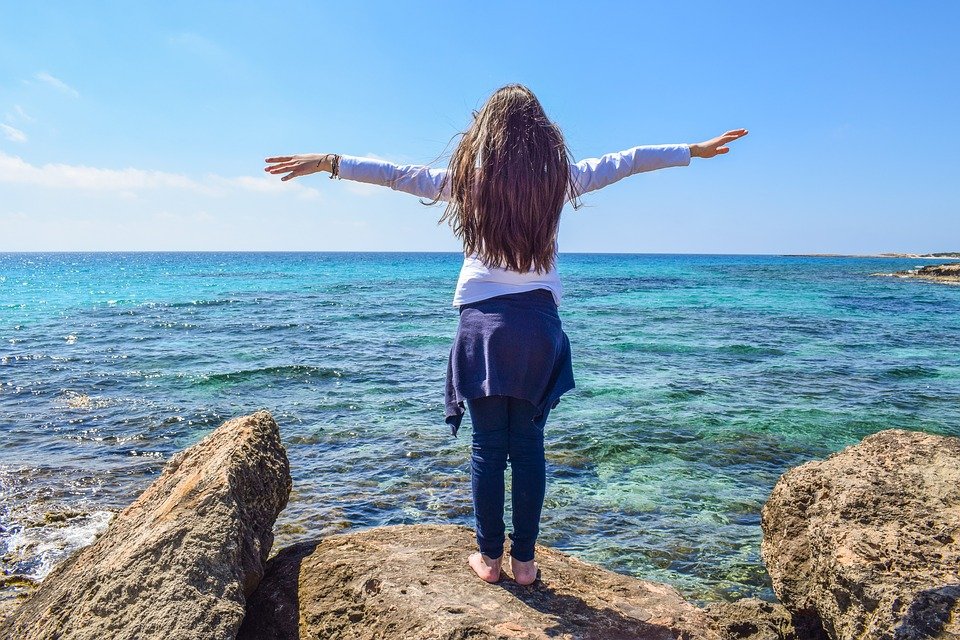 A healthy woman overlooking the sea with her arms stretched out